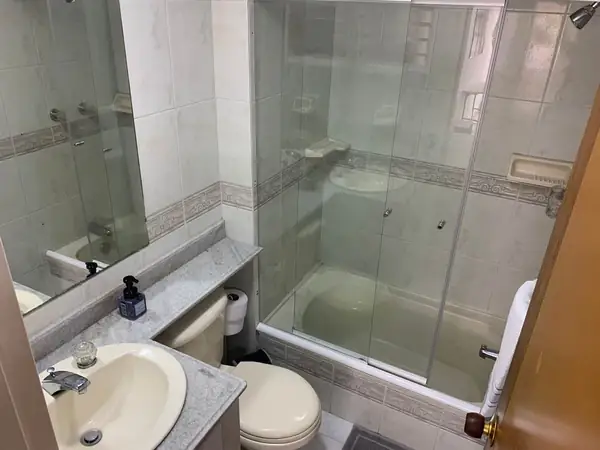Baño con ducha de vidrio y lavamanos