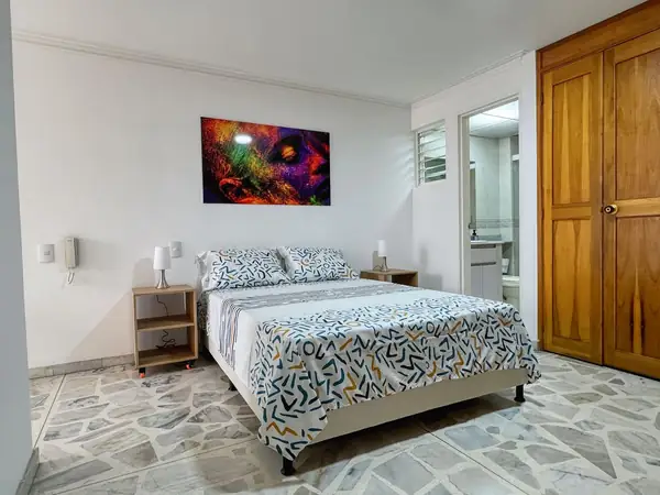 Habitación con cama doble, mesas de noche y closet de madera