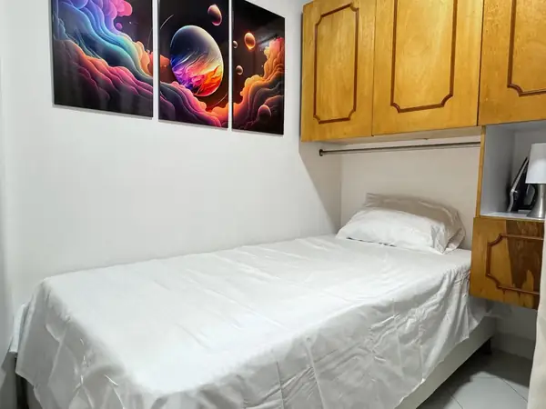 Habitación con cama sencilla y gabinetes de madera
