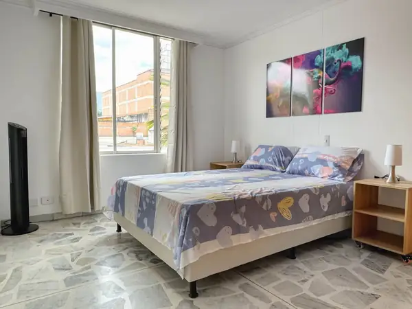 Habitación con cama, ventana y ventilador de torre