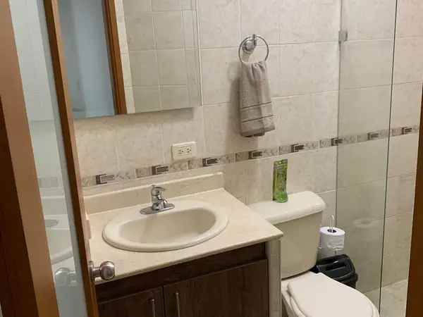 Baño con mueble de lavamanos, espejo y ducha de vidrio