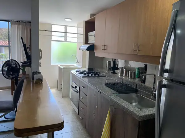 Cocina abierta con barra, estufa a gas y nevera
