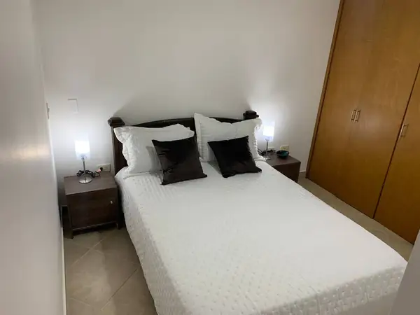 Habitación con cama doble, mesas de noche y closet de madera