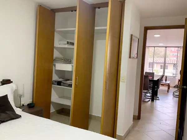 Habitación con closet abierto y vista hacia la sala
