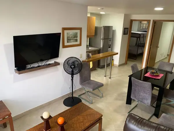 Sala con televisor y comedor, con las habitaciones al fondo