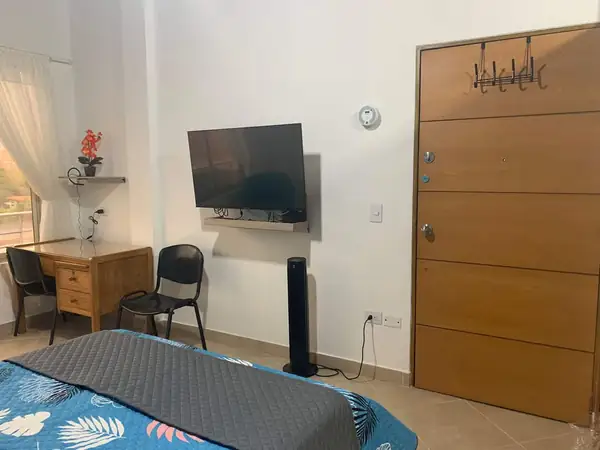 Escritorio, televisor y puerta de entrada del estudio