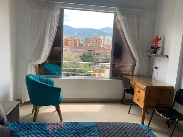 Ventana con vista a la ciudad y a las montañas, sillón y escritorio
