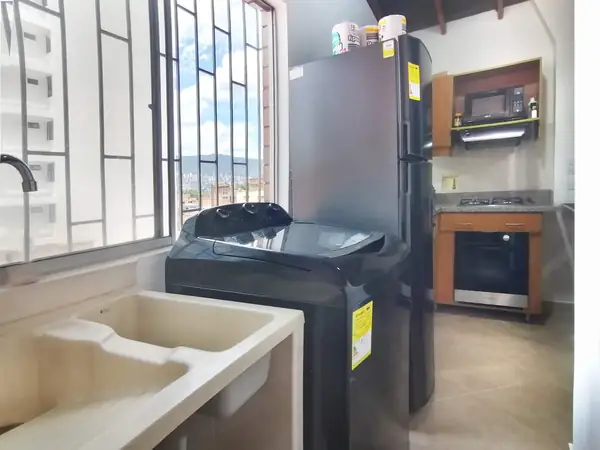 Zona de ropas con lavadora y lavadero junto a la cocina