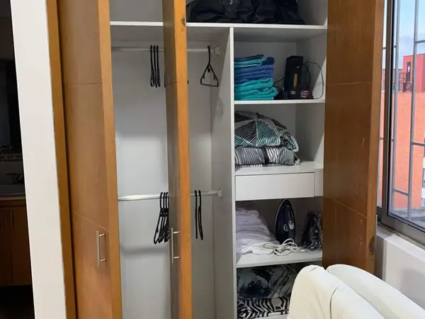 Closet con perchas, toallas, ropa de cama y plancha