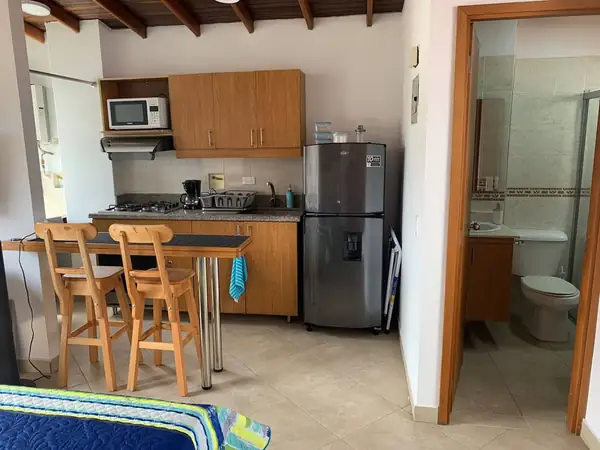 Cocina con barra para dos, nevera y puerta del baño