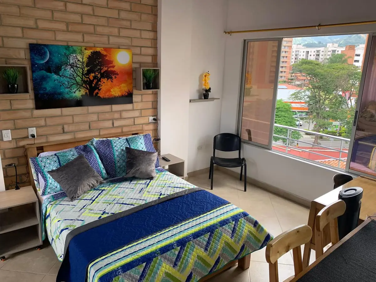 Loft 601 Acacias en Laureles, Medellín, con cama doble y ventanal hacia la ciudad