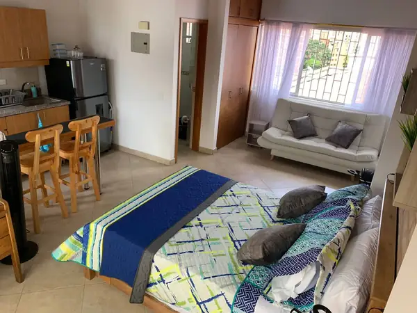Cama doble, sofá cama y cocina en el mismo ambiente
