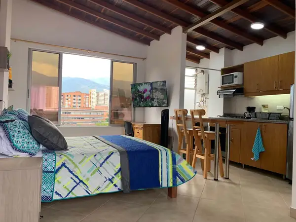 Loft con techo de madera, cama doble y cocina con barra al fondo