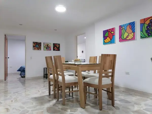 Comedor de madera junto a la sala, con cuadros de colores
