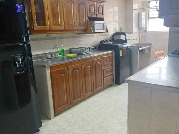 Cocina con nevera, gabinetes de madera y microondas