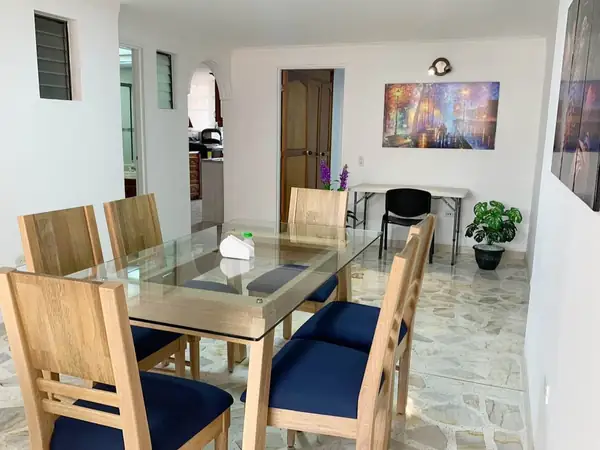 Comedor de madera con sillas azules y una mesa de trabajo al fondo