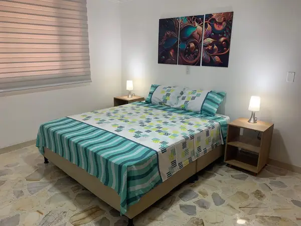 Habitación con cama, dos mesas de noche y persiana